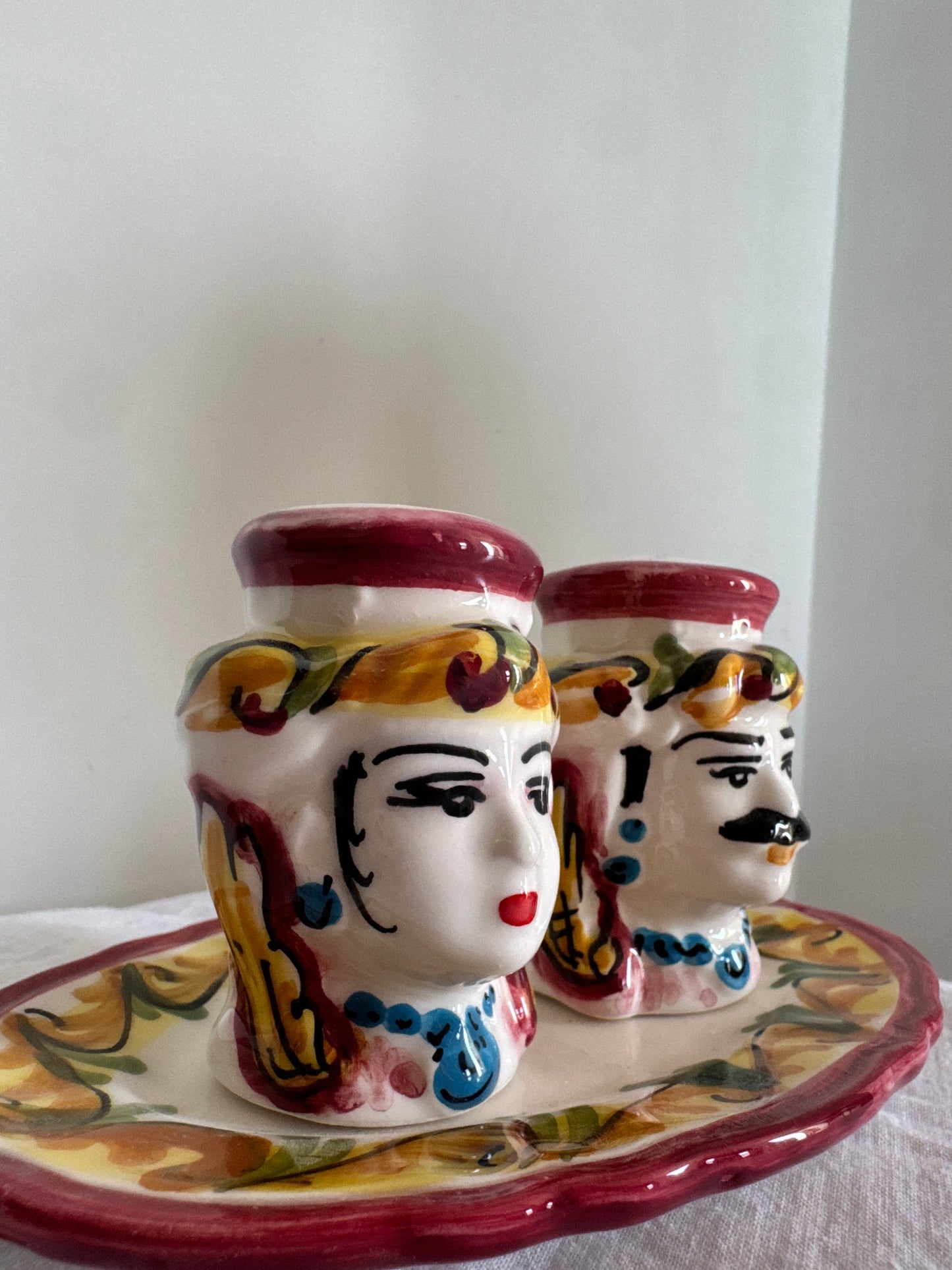 Close-up of handcrafted Sicilian Moor head salt and pepper shakers with hand-painted details and matching tray.