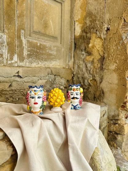 Decorative ceramic pieces on a tablecloth against an old stone wall.
