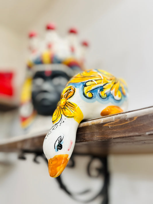 Decorative ceramic goose with colorful patterns on a shelf.