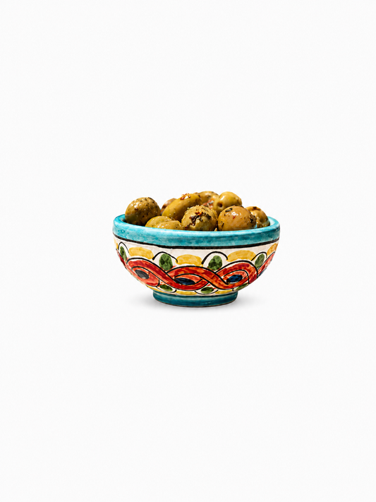 Decorative ceramic bowl with colorful patterns filled with cookies on a white background