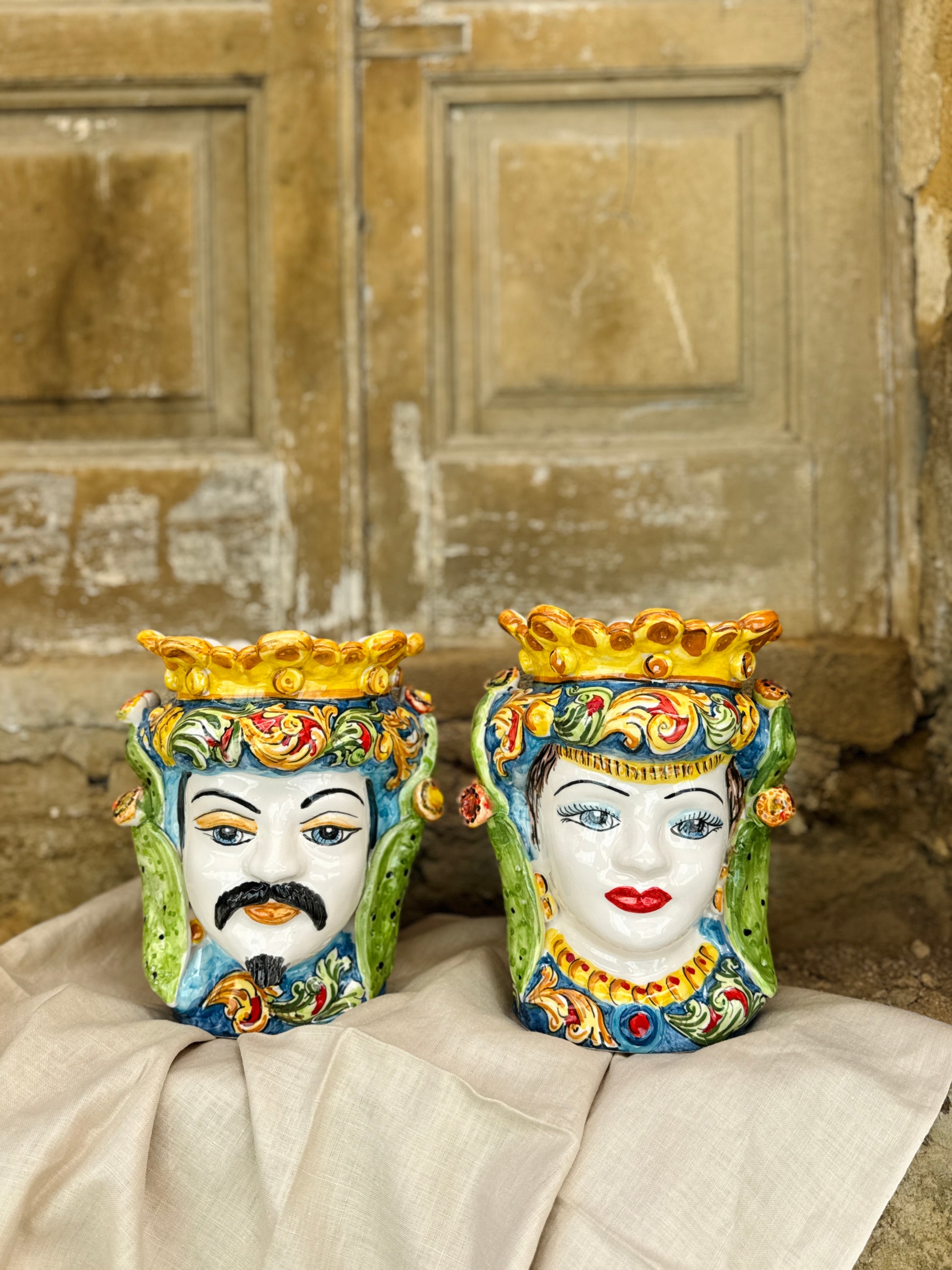 Two decorative masks with colorful faces on a textured surface.