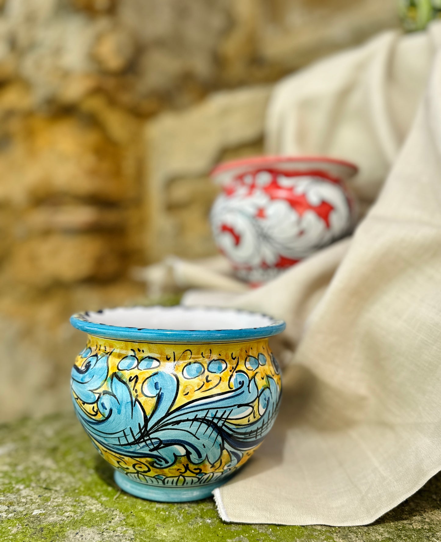 Decorative ceramic cup with blue and yellow patterns on a textured surface.