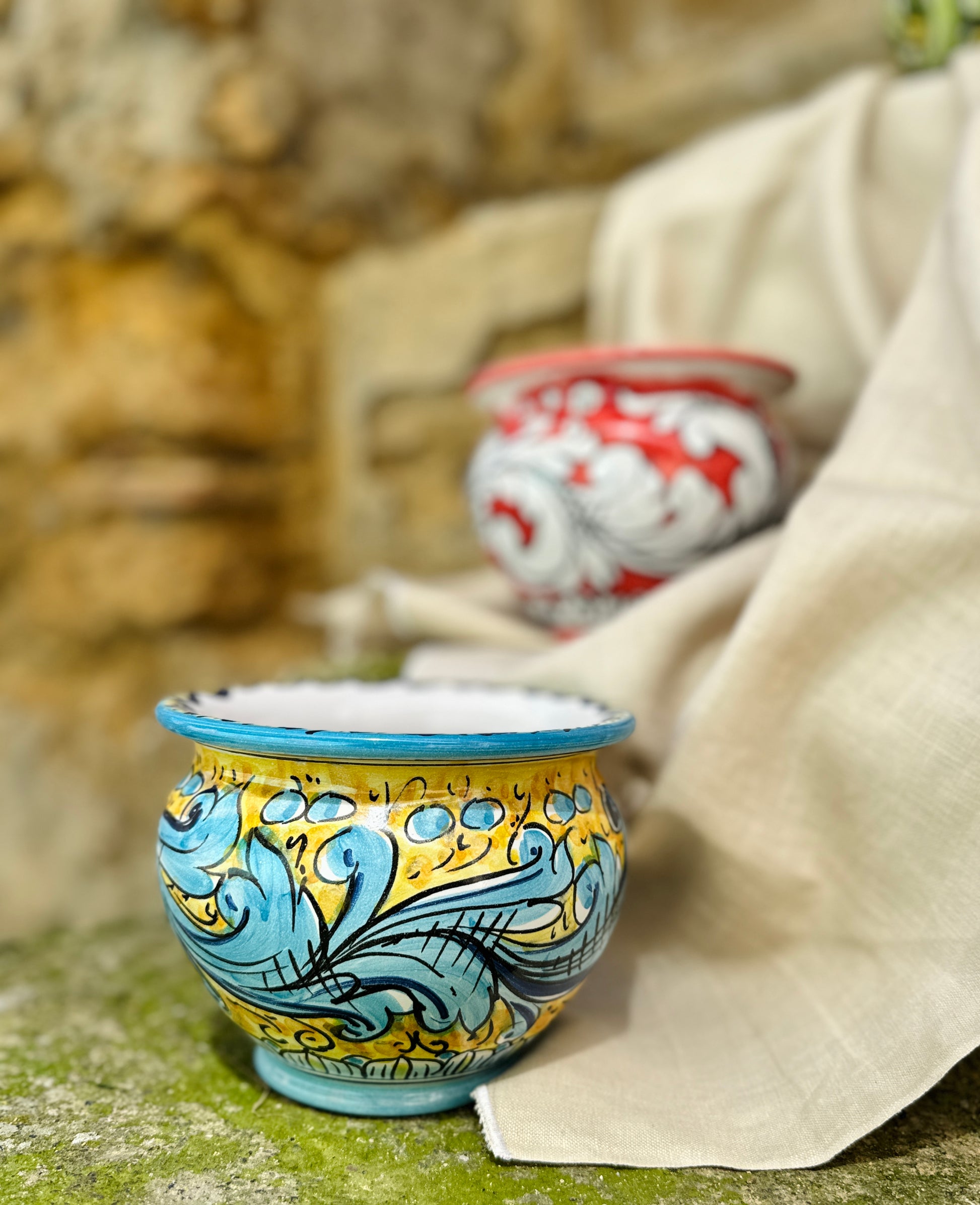 Decorative ceramic cup with blue and yellow patterns on a textured surface.