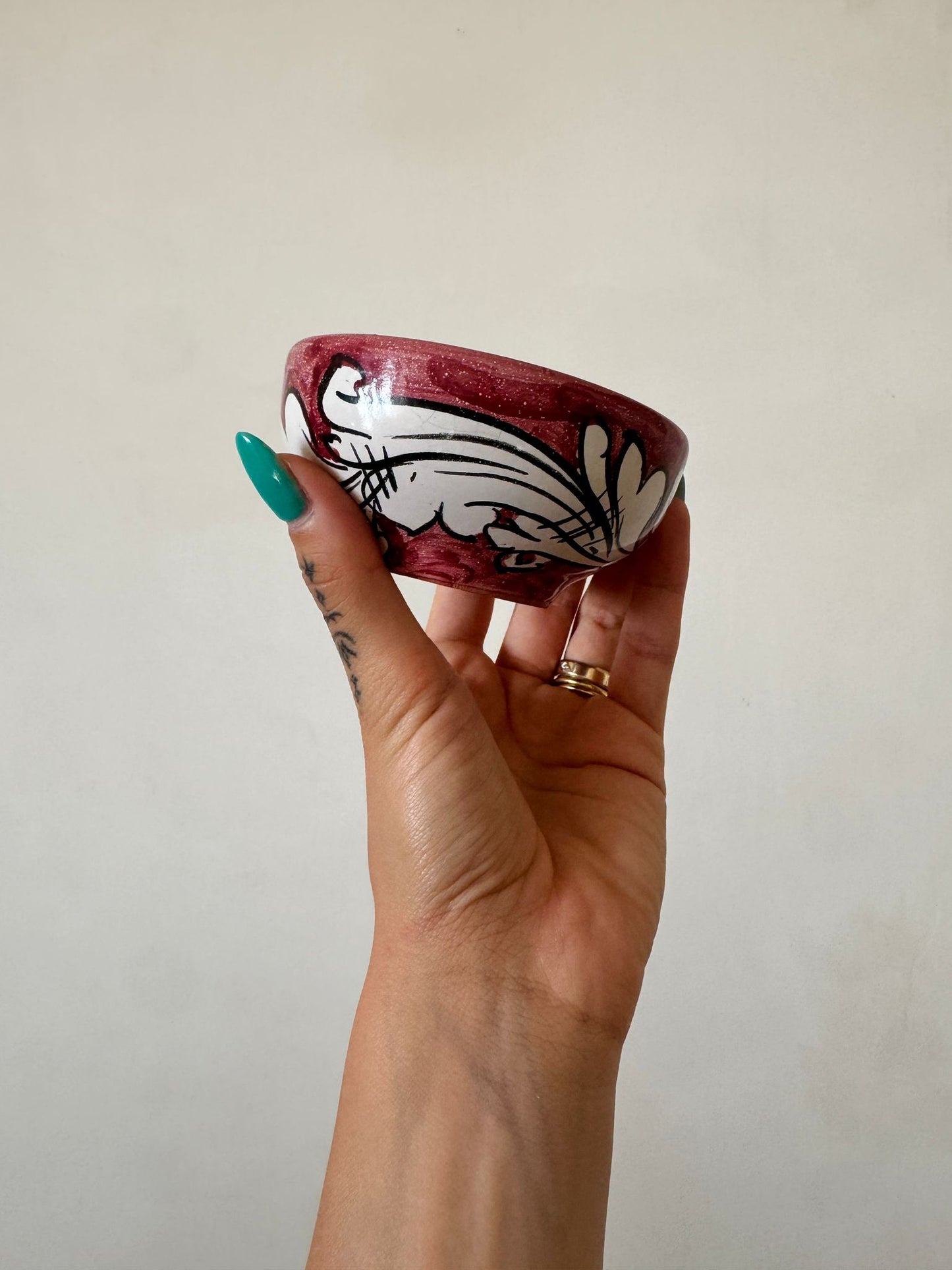 Small handcrafted Sicilian ceramic dipping bowl with burgundy majolica decoration, displayed in hand to showcase artisan craftsmanship and scale.