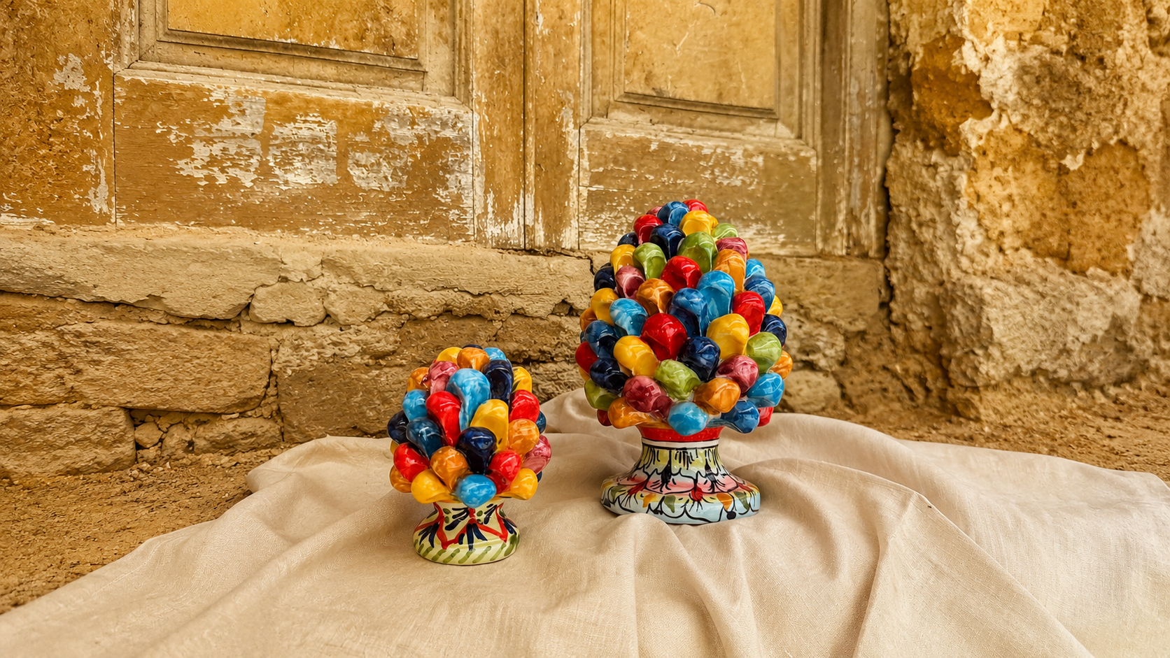 Handcrafted Sicilian ceramic pine cone sculptures from Caltagirone with vibrant multicolor glazed details displayed in a rustic Mediterranean setting.
