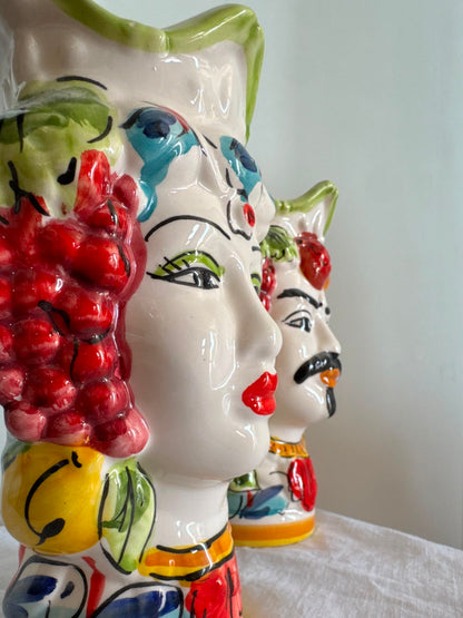 Close-up of handcrafted Sicilian Moor head ceramic vases showing glossy fruit decorations, painted facial details and traditional majolica colors.