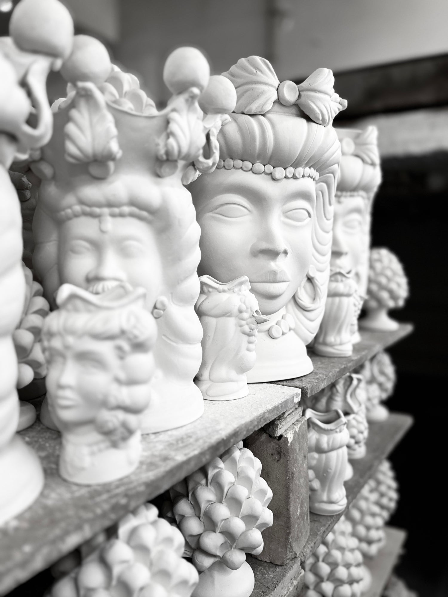 Unfinished Sicilian Moor head ceramic sculptures displayed inside a traditional artisan workshop before glazing and hand painting.