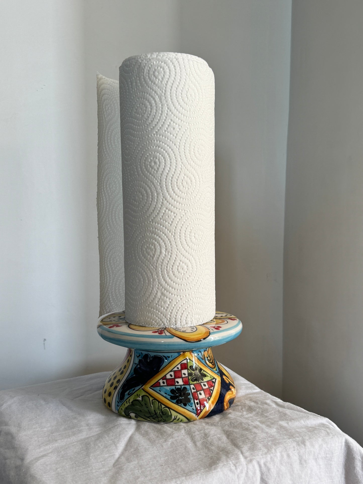 Hand-painted Sicilian ceramic paper towel holder displayed in a kitchen with traditional majolica patterns inspired by Caltagirone craftsmanship.