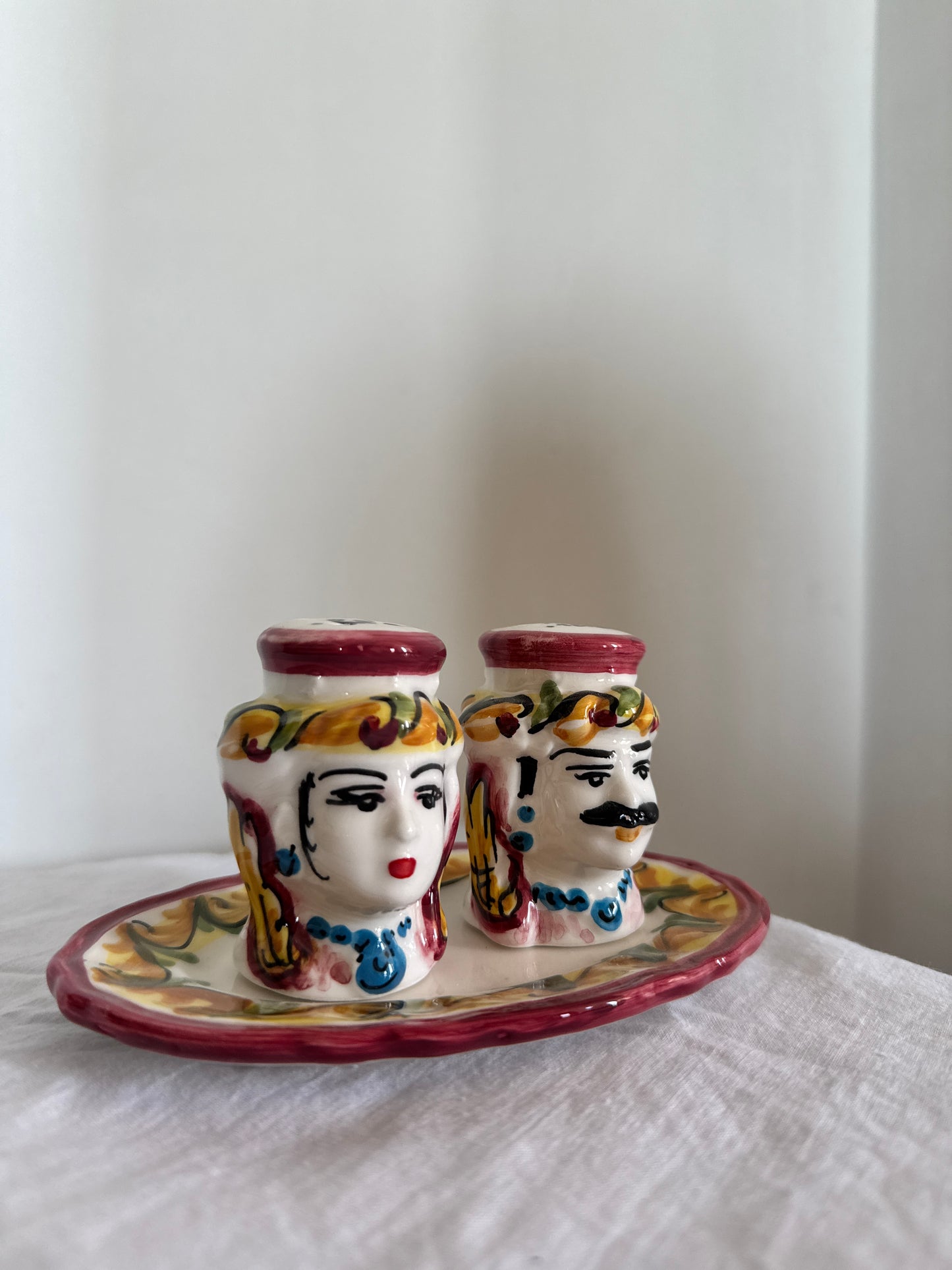 Hand-painted Sicilian Moor head salt and pepper set displayed on a decorative ceramic tray.